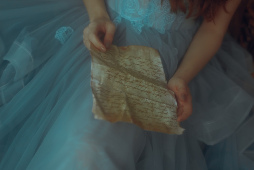 a woman in a blue dress holding a piece of paper