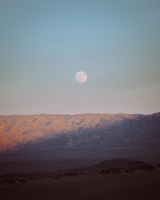 Wide shot of the desert landscape bathed in moonlight with silhouettes of drummers.