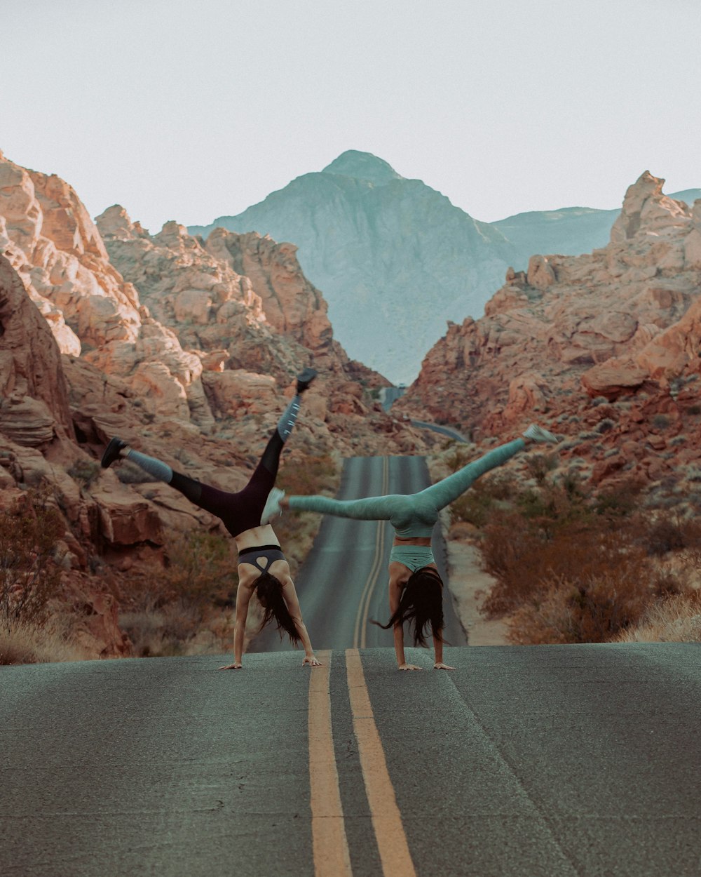 woman doing handstand on asphalt road