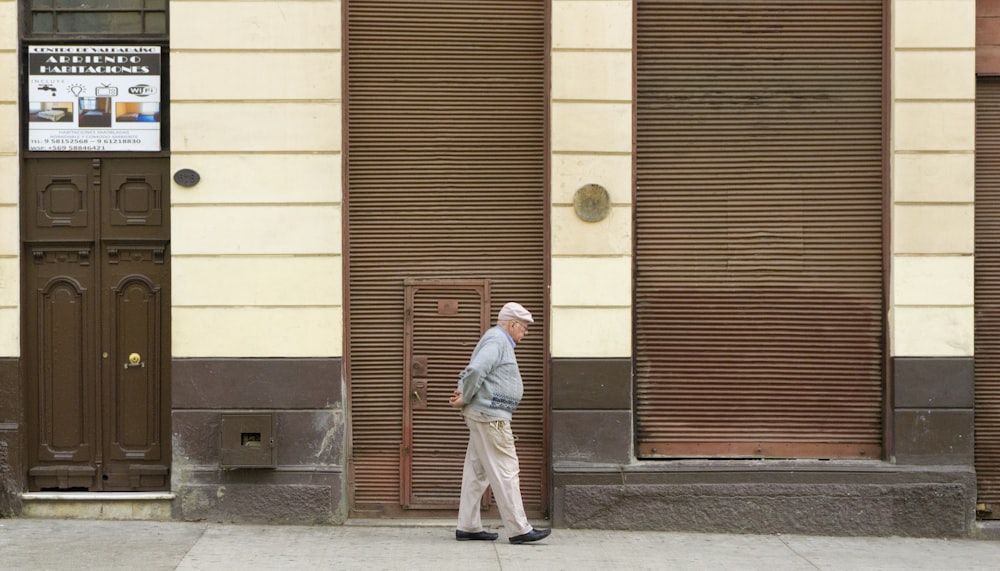 man wearing gray sweater walking on street