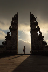woman wearing beige dress in the middle of arch temple