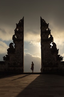 woman wearing beige dress in the middle of arch temple