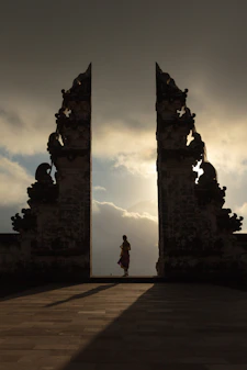woman wearing beige dress in the middle of arch temple