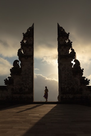 woman wearing beige dress in the middle of arch temple