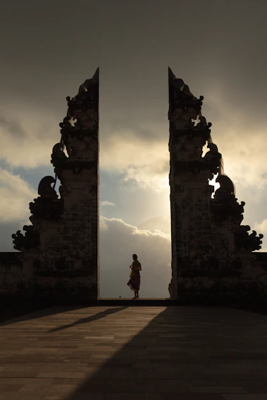 woman wearing beige dress in the middle of arch temple