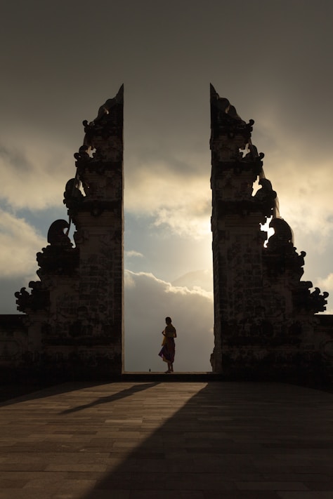 woman wearing beige dress in the middle of arch temple
