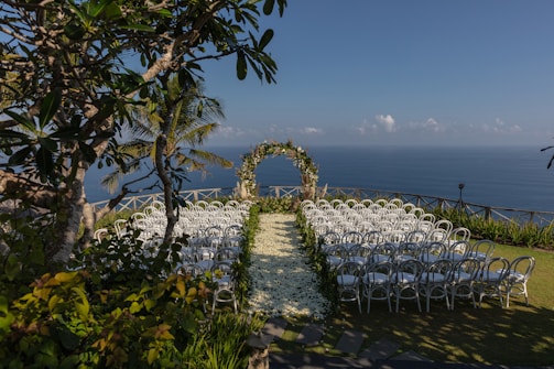 white chairs and green and white floral arch