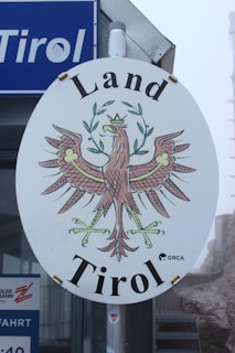 A vibrant outdoor banner displayed on a busy street in Tirol.