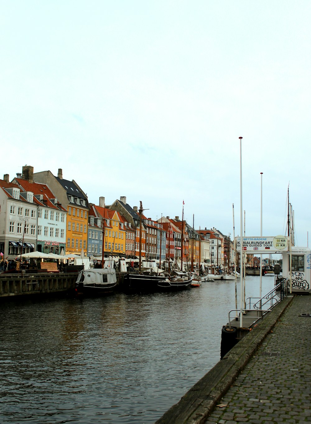 yellow, red, and white houses facing body of water under white sky