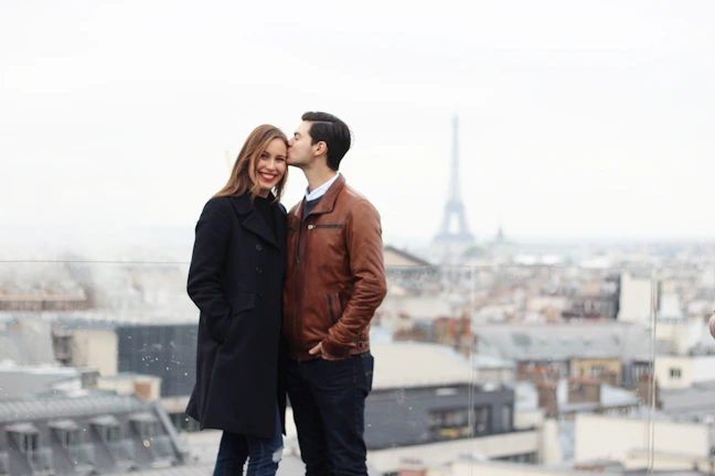 A smiling couple enjoying a cozy Parisian apartment balcony view at sunset