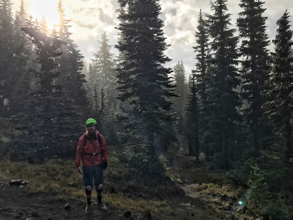 man standing beside pine trees