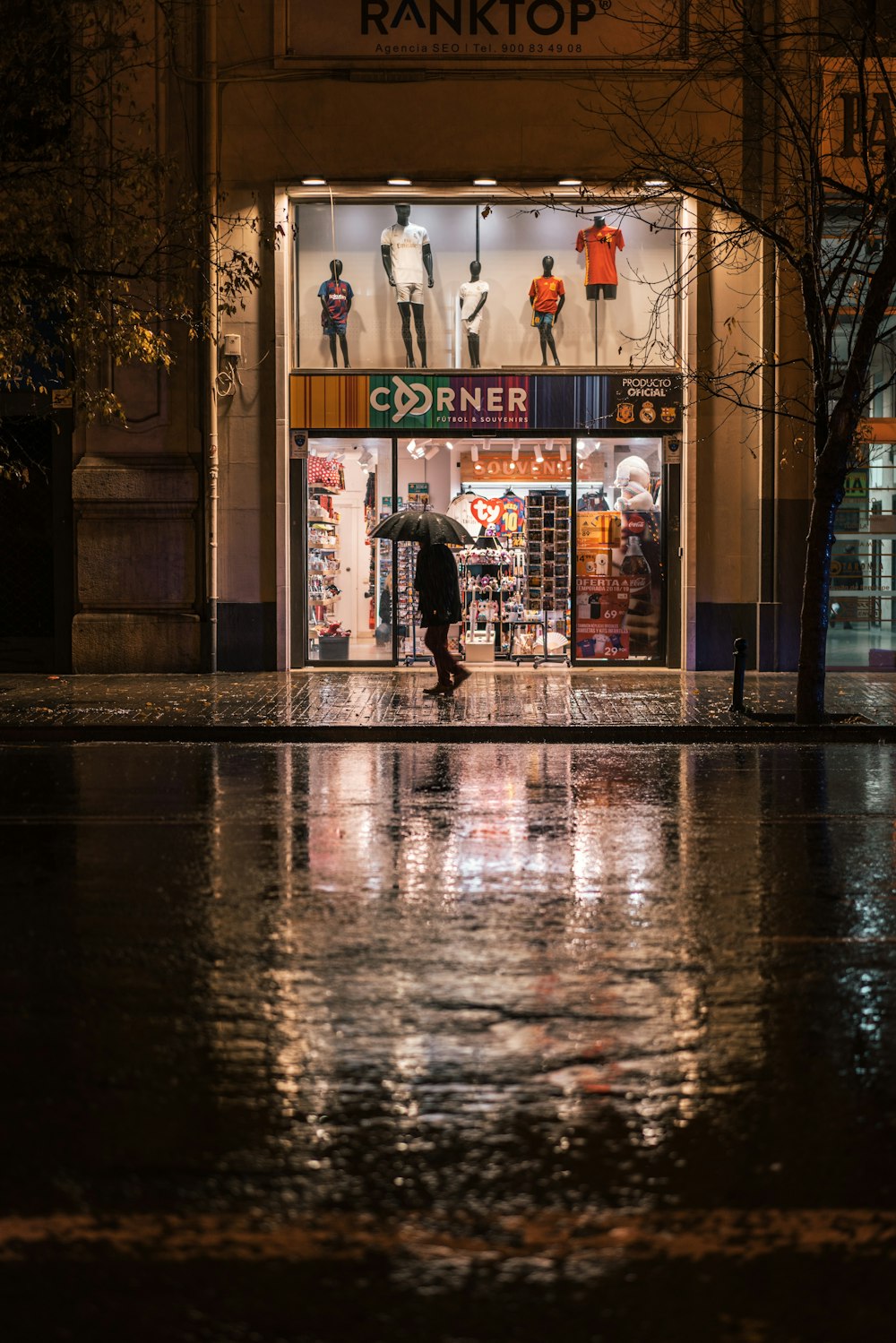 silhouette of person walking on street using umbrella