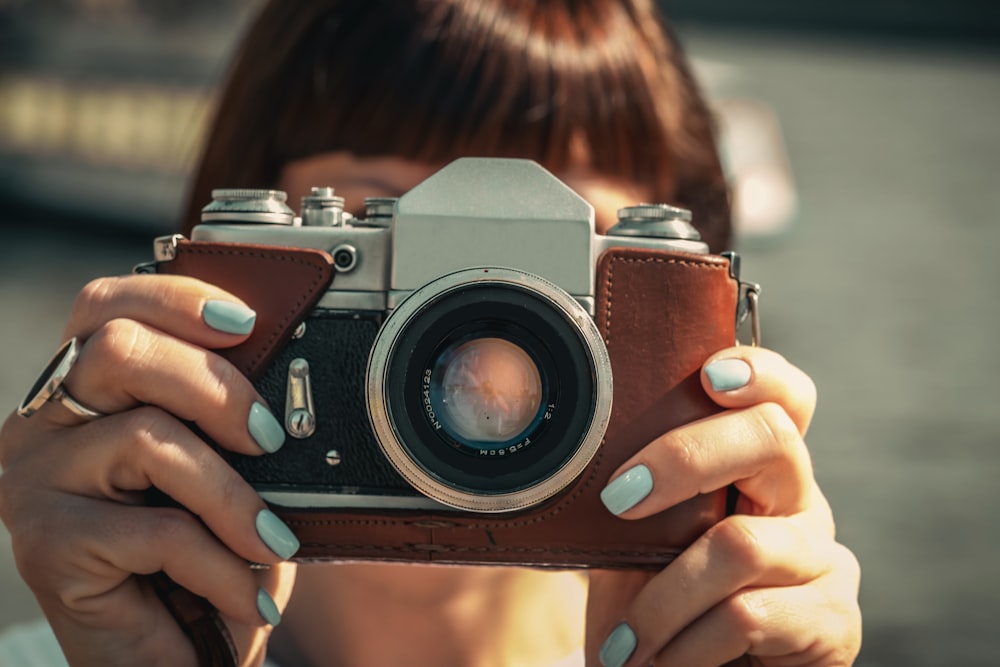 woman holding brown and grey camera