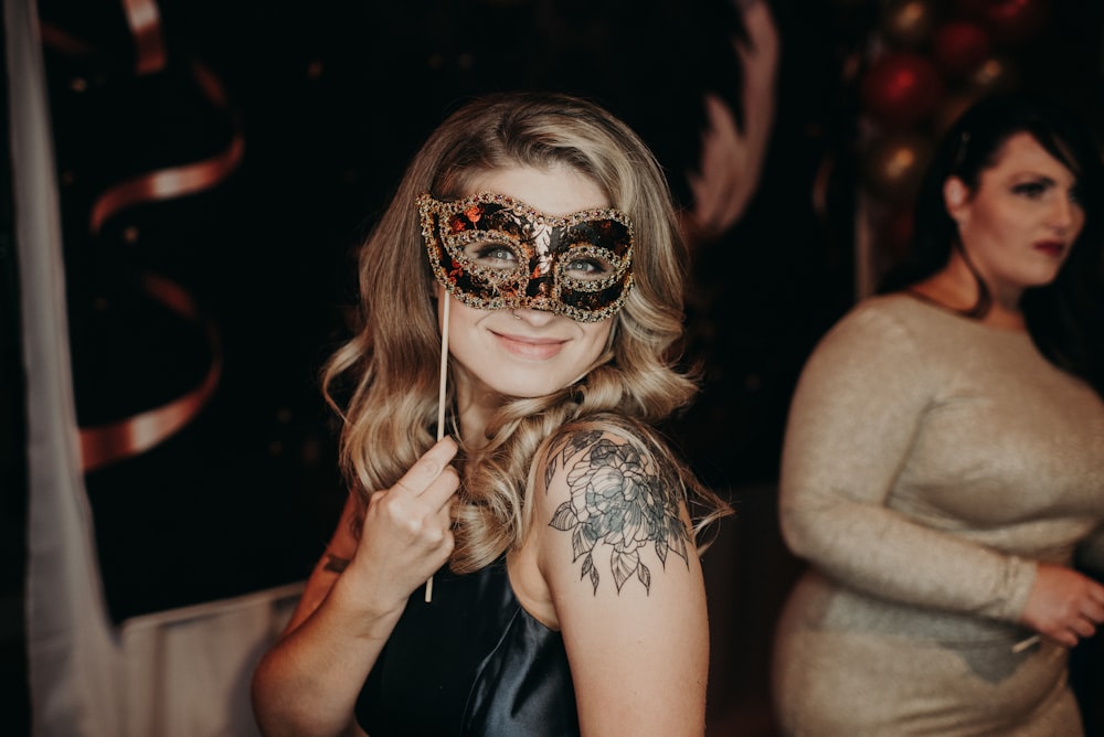 woman wearing black dress and black and gold mask