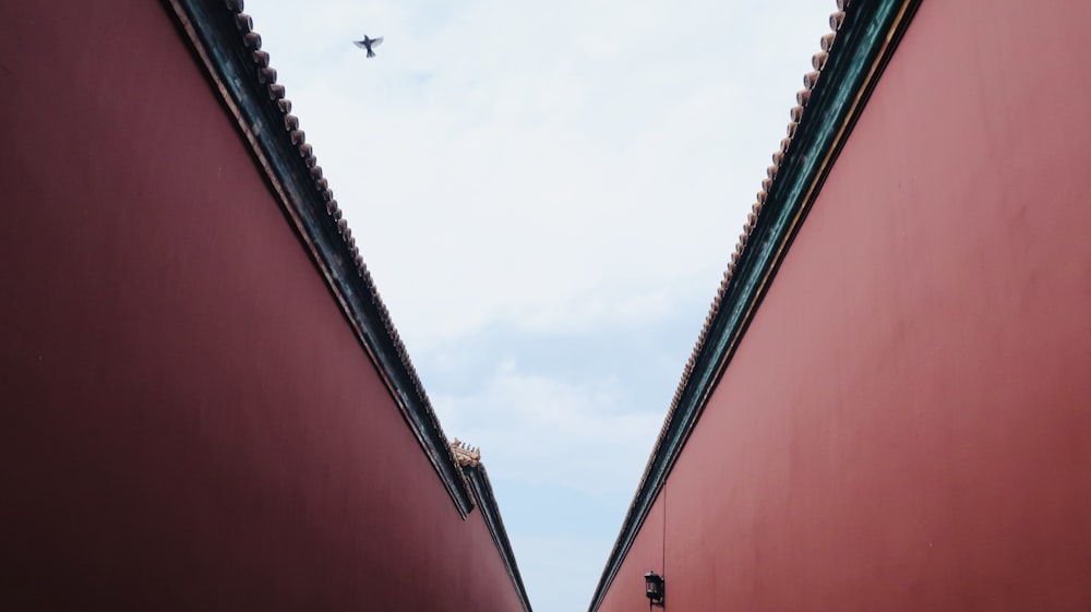 an airplane is flying over two red buildings