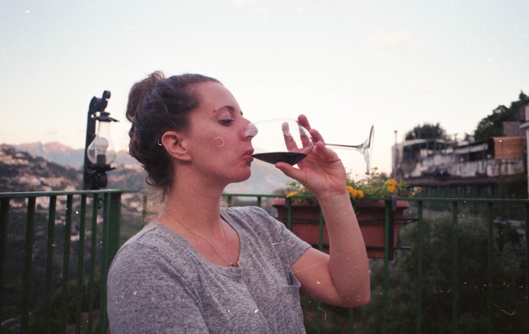 woman drinking wine outside house during daytime