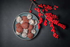 Assortment of chocolate truffles with various toppings arranged on a ceramic plate.