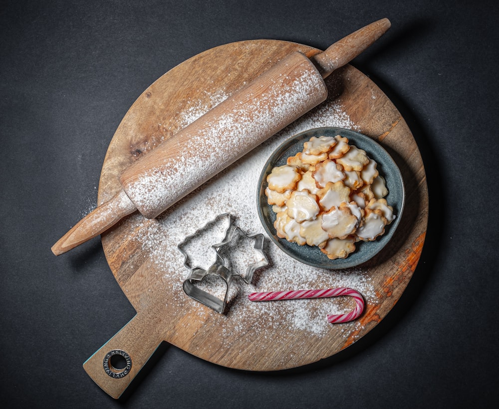 brown wooden rolling pin and pizza pan with cookie cutters