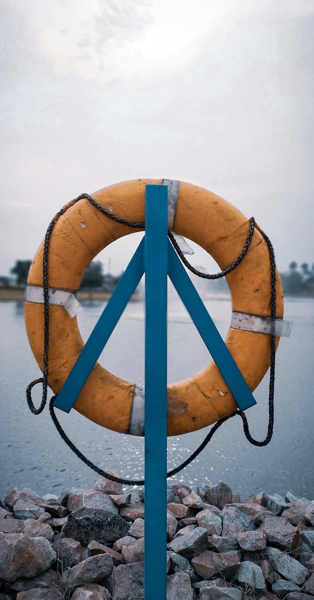 orange lifebuoy hanging on post near water