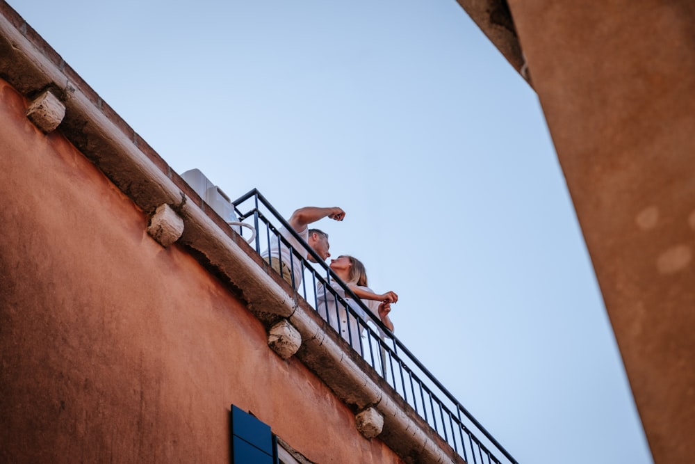 man wearing whtie crew-neck shirt and woman wearing white blouse talking on roof