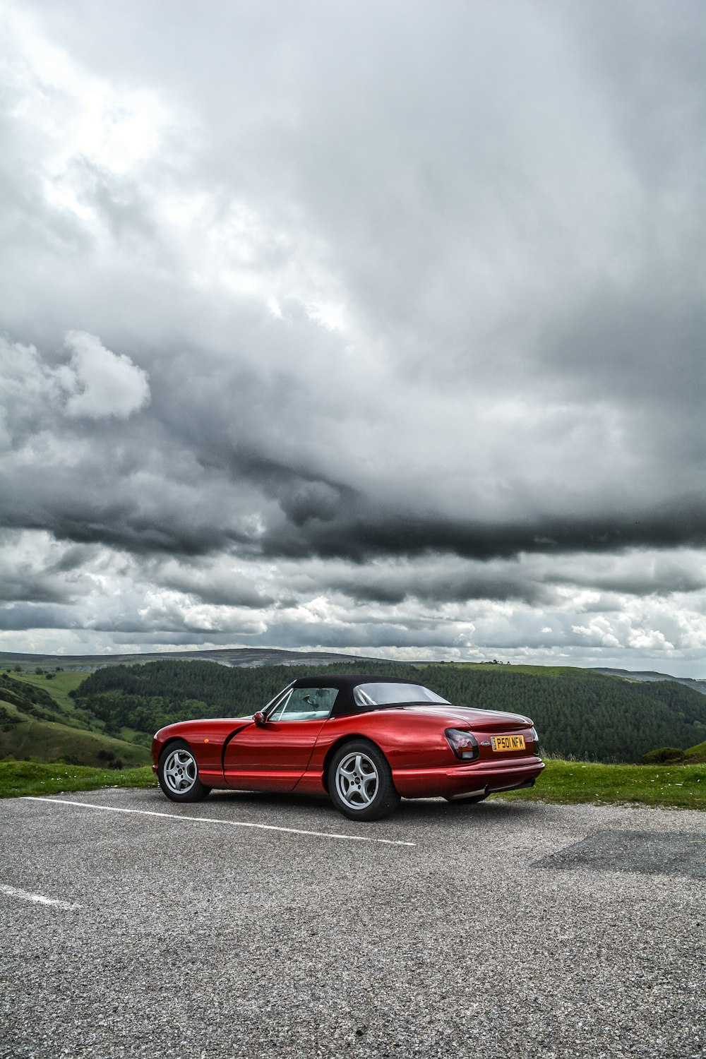 red convertible coupe parking under cloudy sky