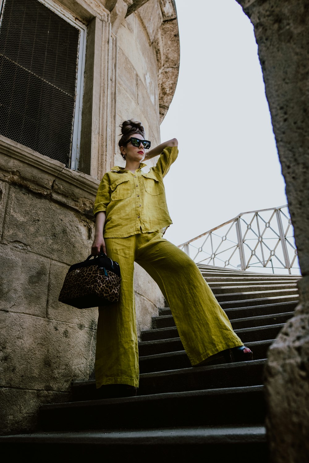 woman in green shirt and pants standing on staircase