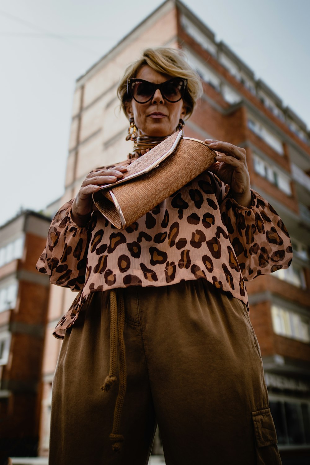 low-angle photography of standing woman holding purse near building during daytime