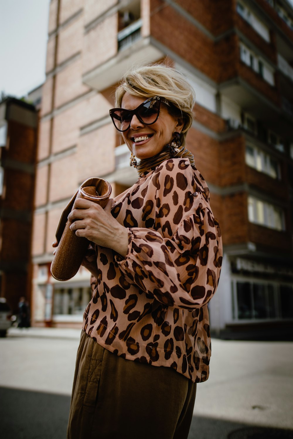 Mujer con blusa marrón y beige sosteniendo bolso de bolsa marrón