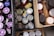 Various food items are stored in wooden crates. The assortment includes cans with green pull tabs, jars with purple lids, bottles, and boxes. The items are tightly packed, suggesting storage or organization.