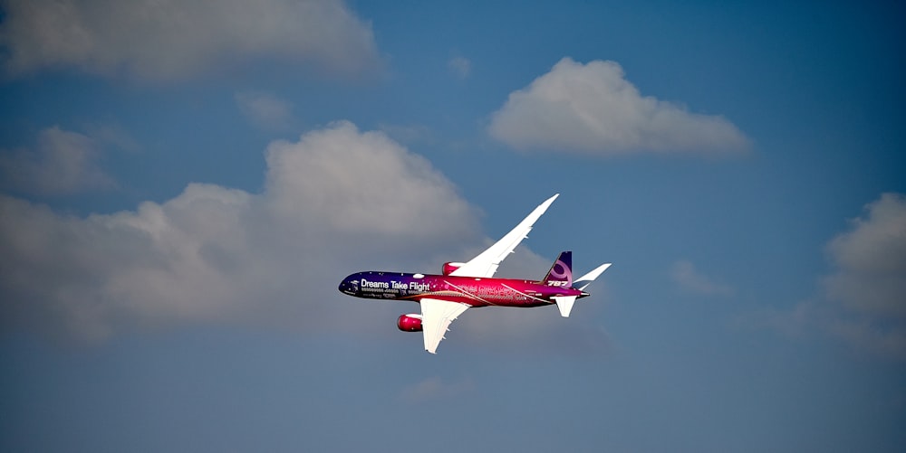 red and white airplane flying during daytime