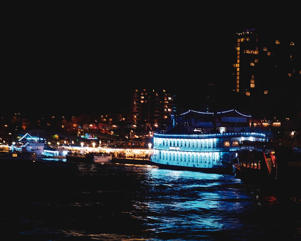 lighted concrete buildings beside ocean at night