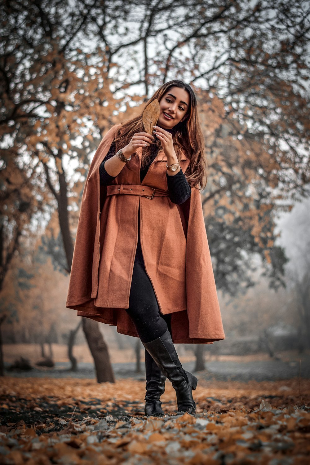woman wearing brown coat holding brown leaf