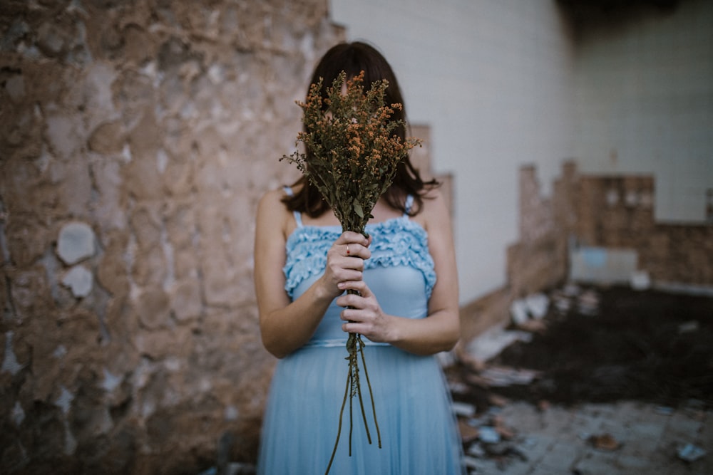 woman wearing blue dress near wall