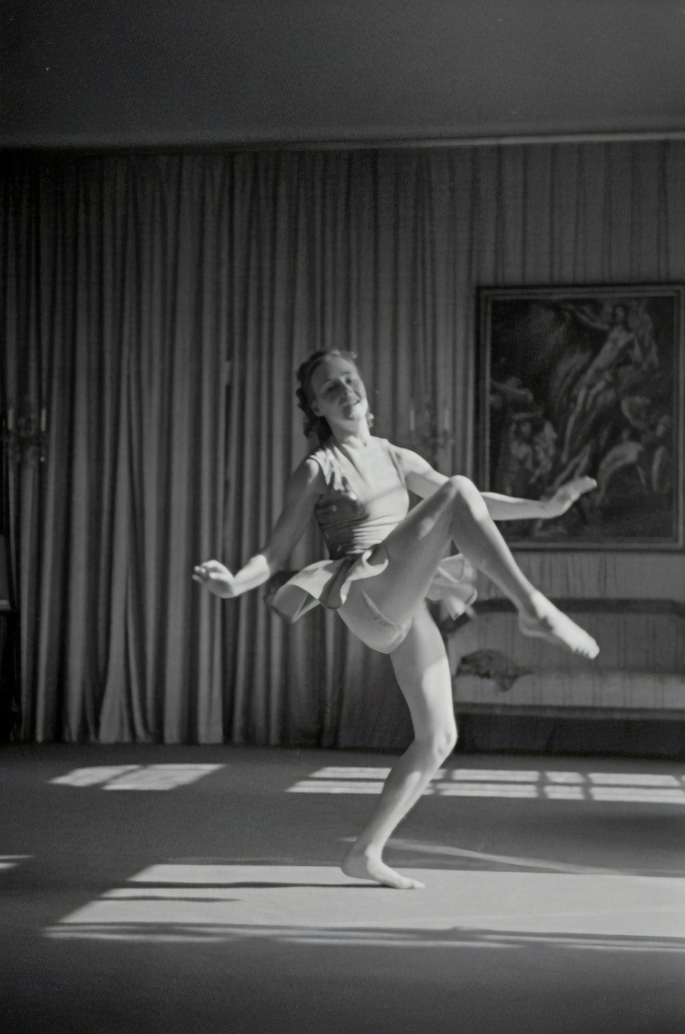 grayscale photo of woman dancing near curtain