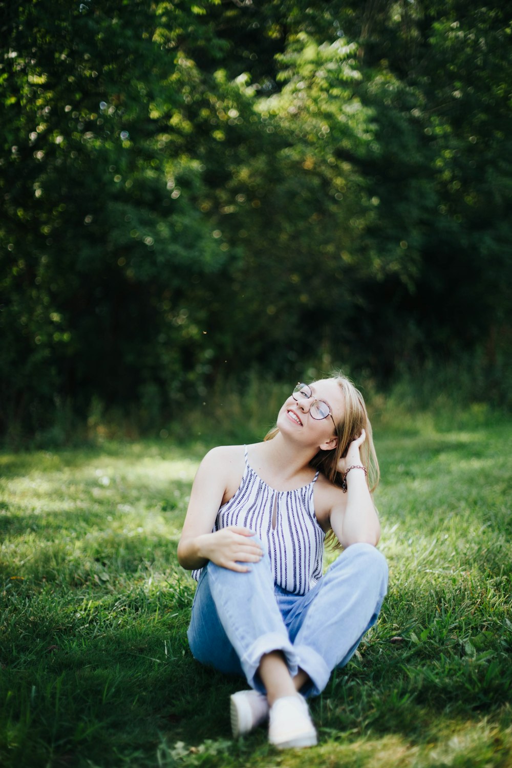 donna in blue jeans che si siede sul campo dell'erba