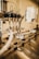 A close-up view of an industrial machine component featuring multiple metal pipes and mechanical parts. Various cables are connected, and the setting appears to be a factory or manufacturing environment. The image has a warm, metallic look with reflections off the metal surfaces.