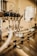 A close-up view of an industrial machine component featuring multiple metal pipes and mechanical parts. Various cables are connected, and the setting appears to be a factory or manufacturing environment. The image has a warm, metallic look with reflections off the metal surfaces.