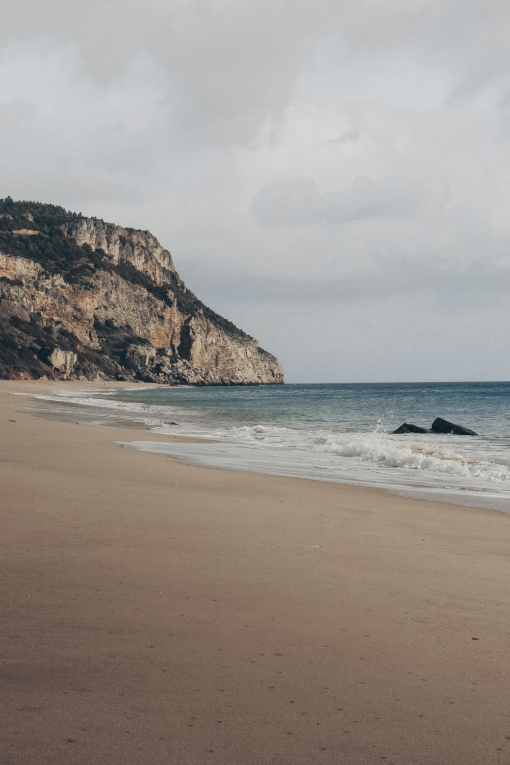 a sandy beach with a mountain in the background