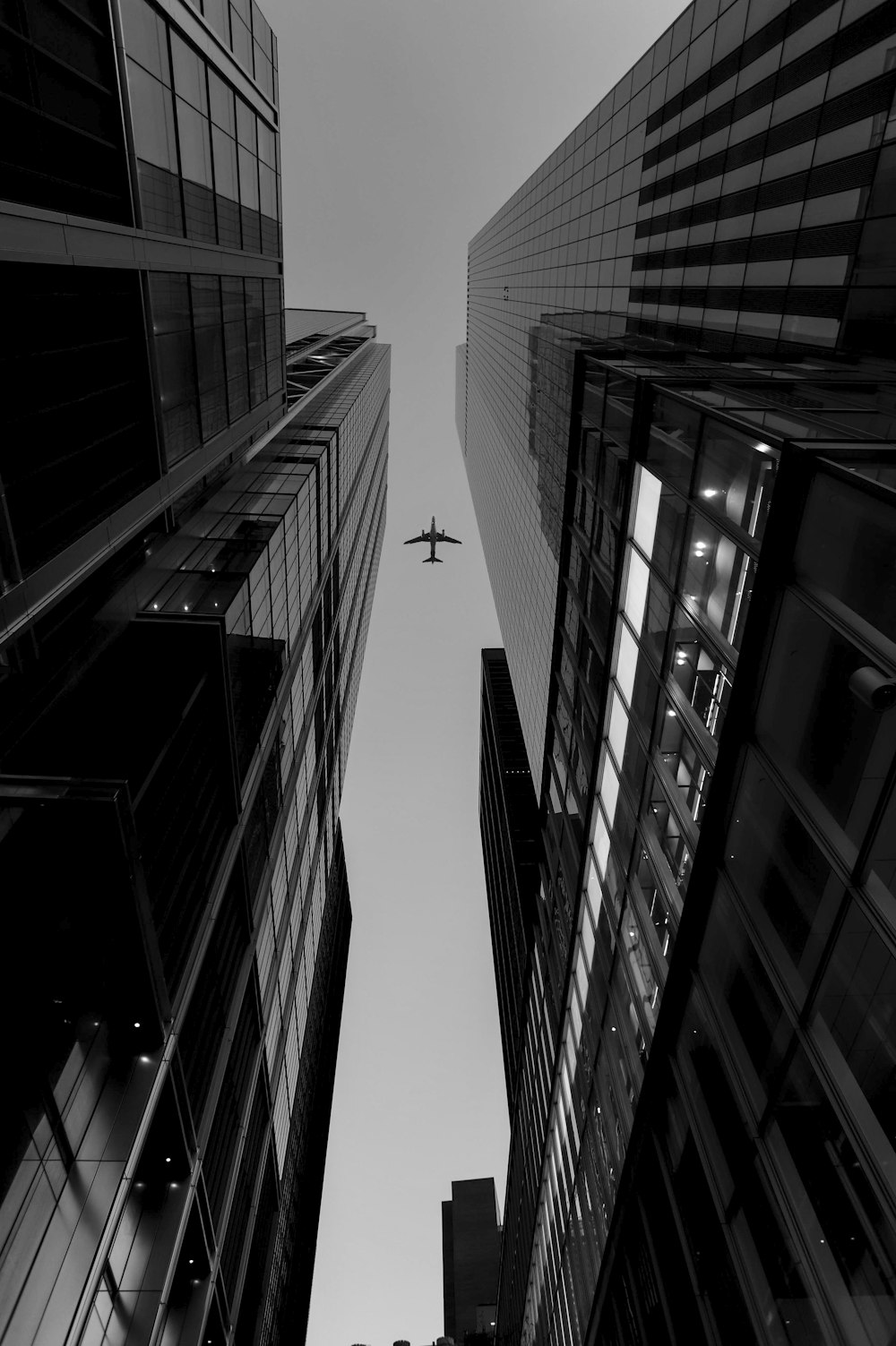 grayscale photo of airplane between buildings