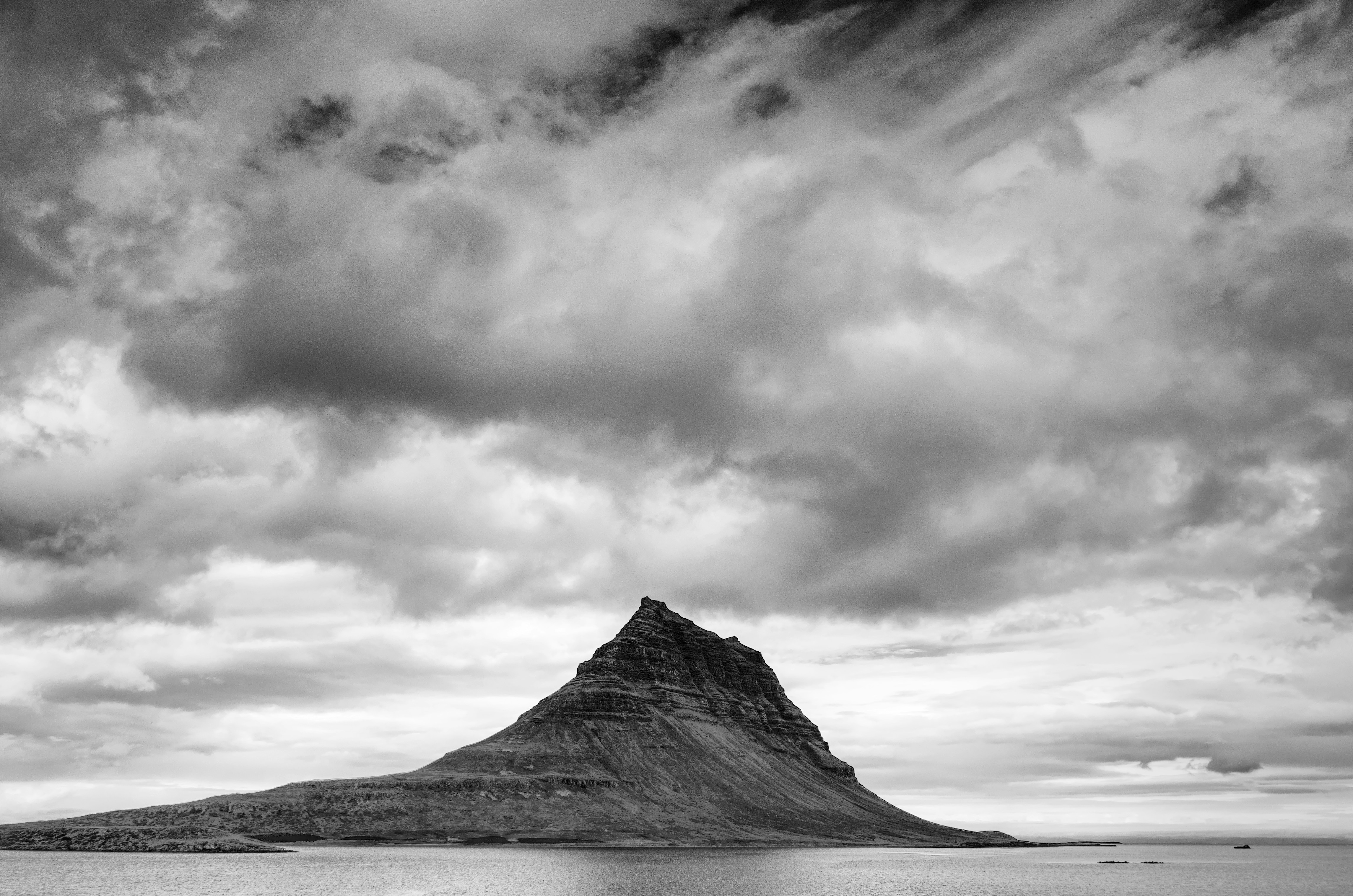 grayscale photography of island under cloudy sky