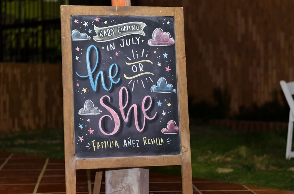 brown framed chalkboard easel with baby coming in July he or she text