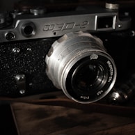 Close-up of a vintage film camera with textured leather grip and shiny metal accents.