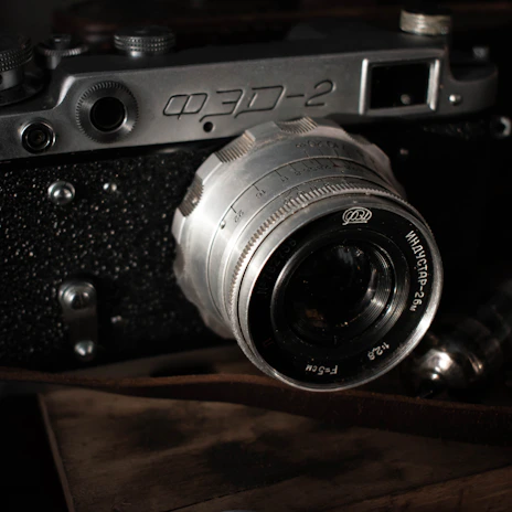 Close-up of a vintage film camera with textured leather grip and shining lens.