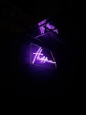 Shopfront sign featuring a bold, custom logo glowing under soft purple lighting.