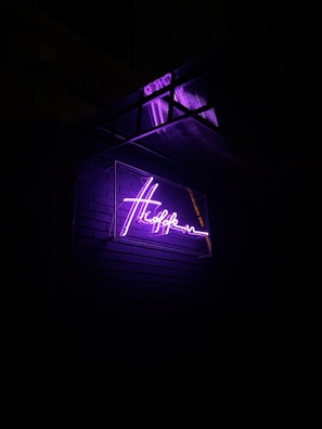 Shopfront sign featuring a bold, custom logo glowing under soft purple lighting.