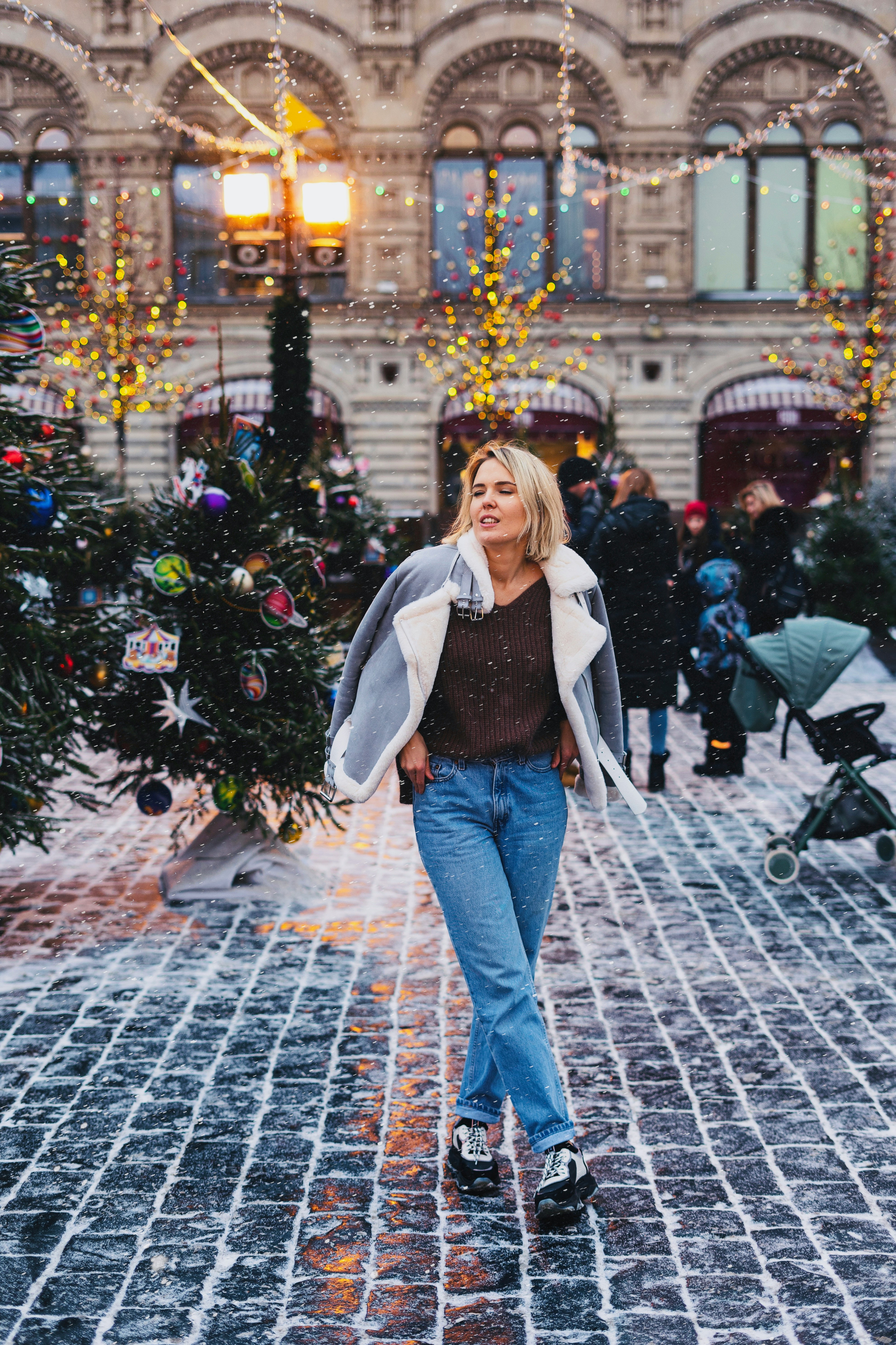 woman in jacket near Christmas trees on road