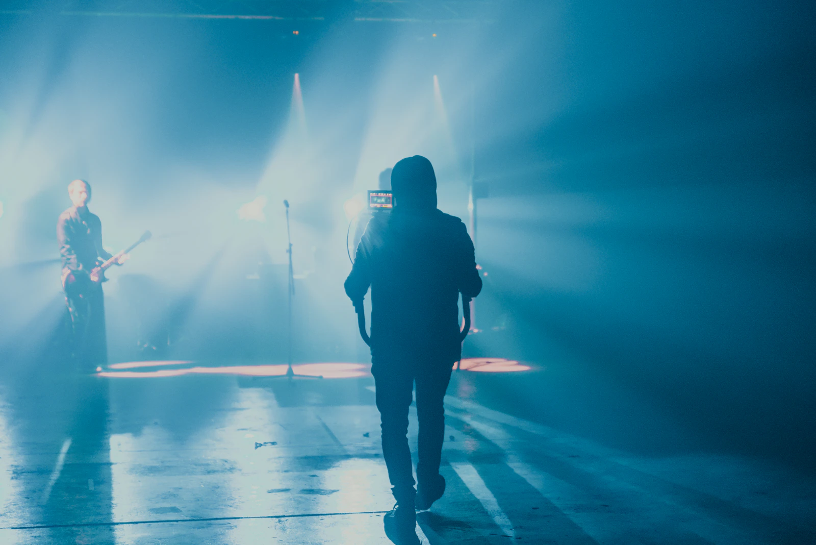 Musician on a smoky blue-lit stage with a camera operator