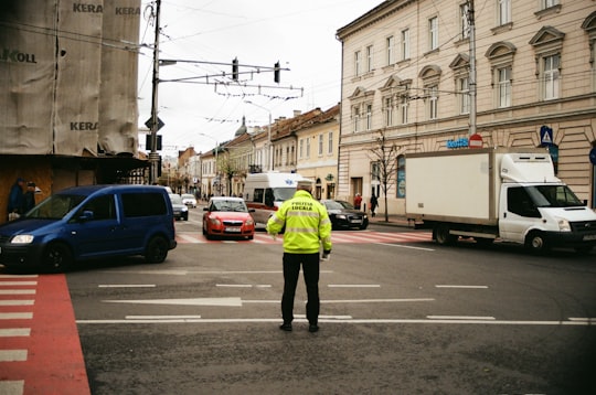 man in green jacket and black pants standing on road during daytime in Cluj-Napoca Romania