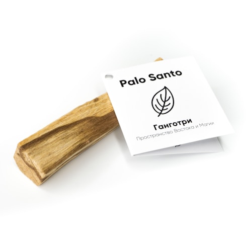 A piece of Palo Santo wood is accompanied by a white card that features the text 'Palo Santo' and a leaf illustration. The card includes additional text in another language, suggesting a connection to spirituality or cultural traditions. The wood appears natural and unfinished, with a smooth texture.