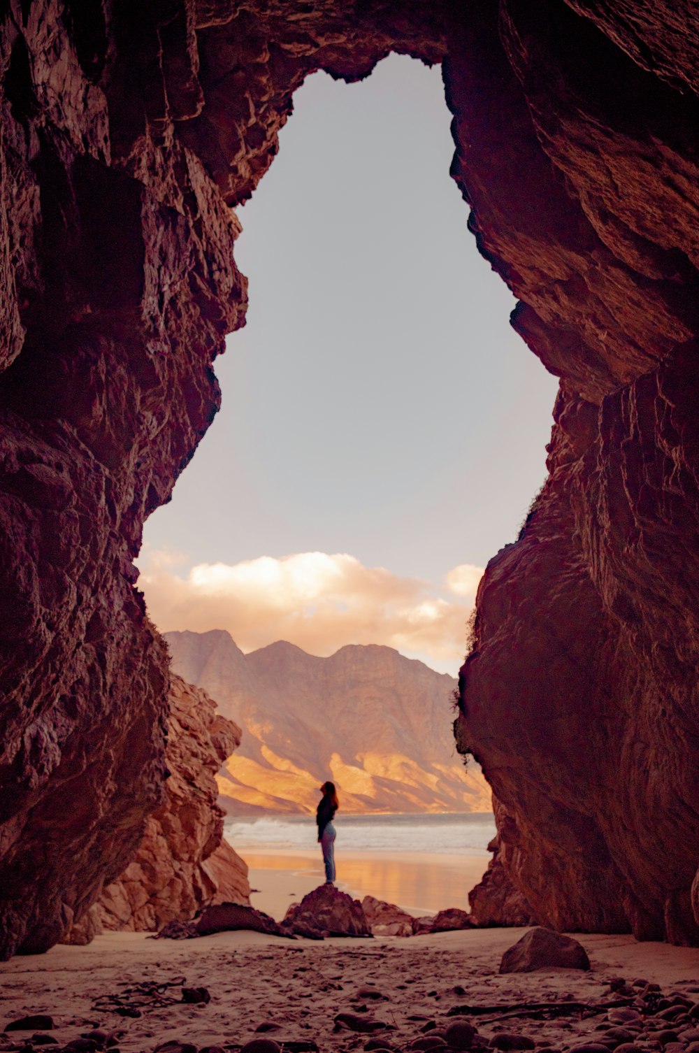 silhouette of person standing on top of rock during daytime